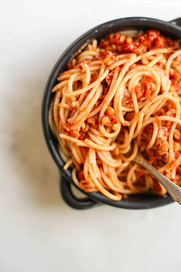 a bowl of vegan meat sauce on spaghetti with a fork sticking out of it.