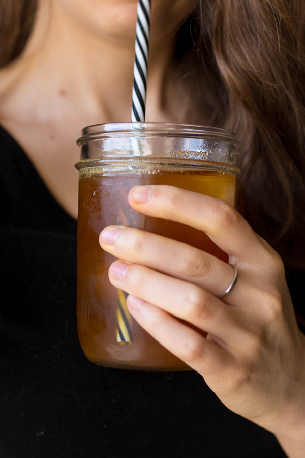 girl holding a cup of cinnamon turmeric iced tea with a straw