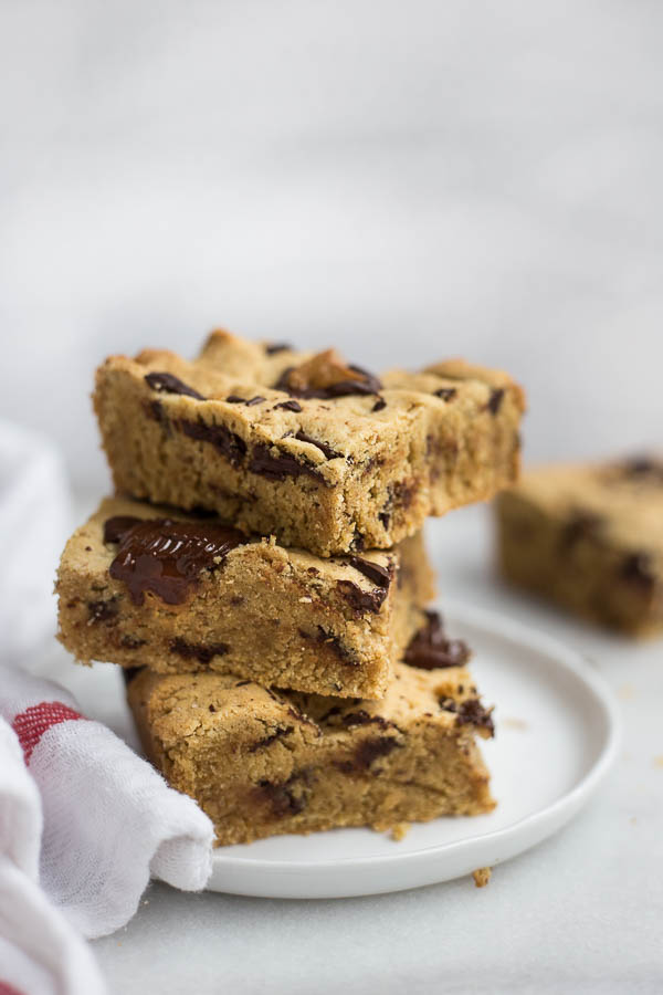 Vegan Peanut Butter Cup Blondies: Dense and chewy blondies are filled with peanut butter cups and dark chocolate! Naturally gluten free, vegan, and refined sugar free and ready in 30 minutes! || fooduzzi.com recipe
