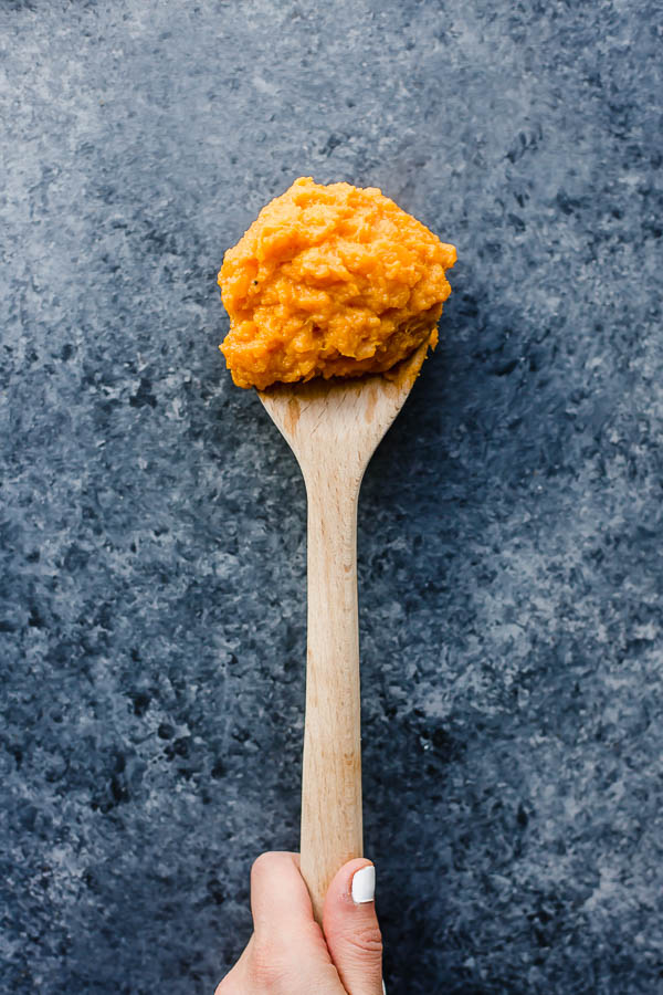 a wooden spoon with sweet potato mash