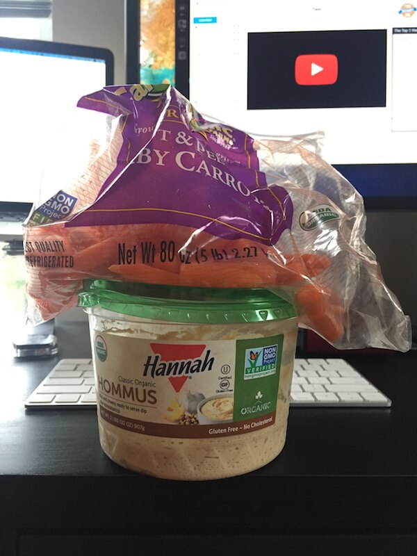 a bag of baby carrots and a tub of hummus