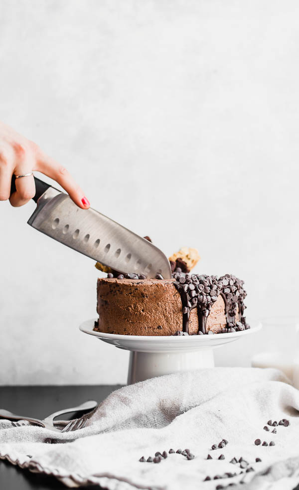 slicing chocolate cake on a cake stand