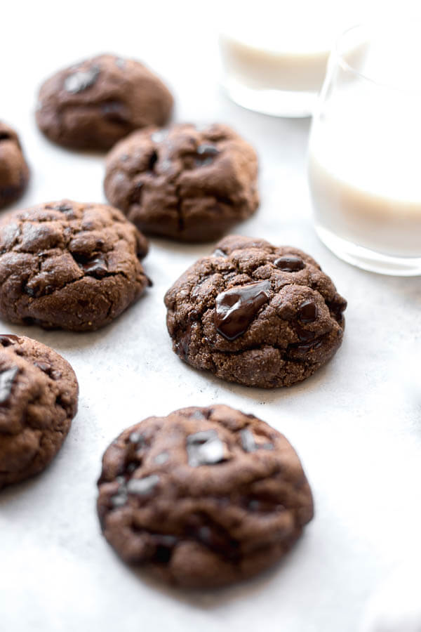 chocolate cookies on a white background with two glasses of milk