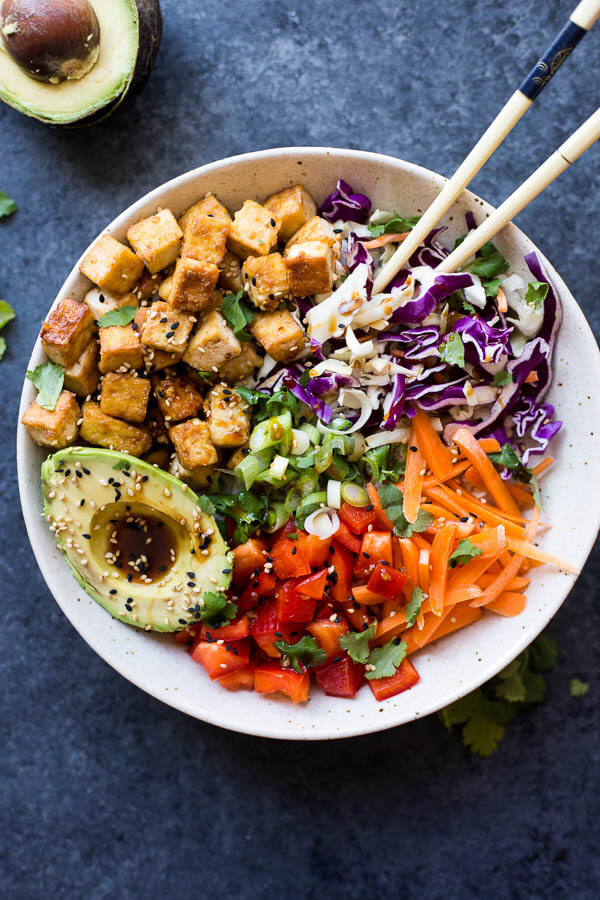 vegetables and crispy tofu in a bowl with chopsticks