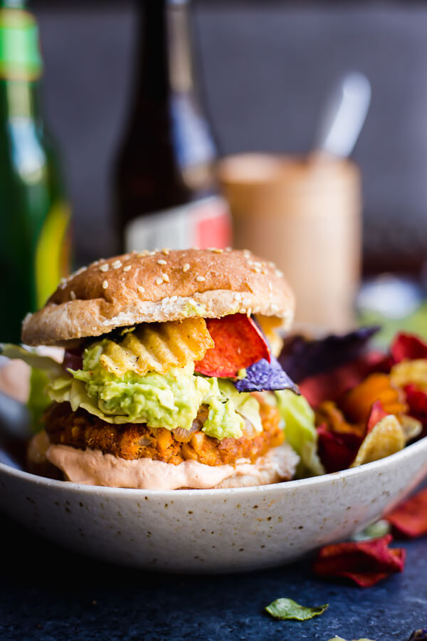 a plate with vegan guacamole crunch burger and chips