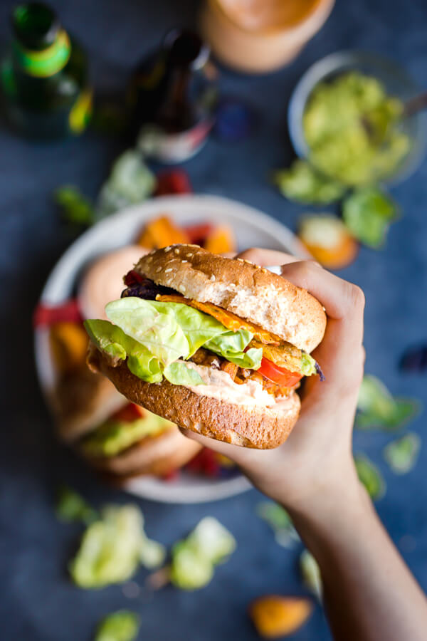 a vegan guacamole crunch burger being held over a plate