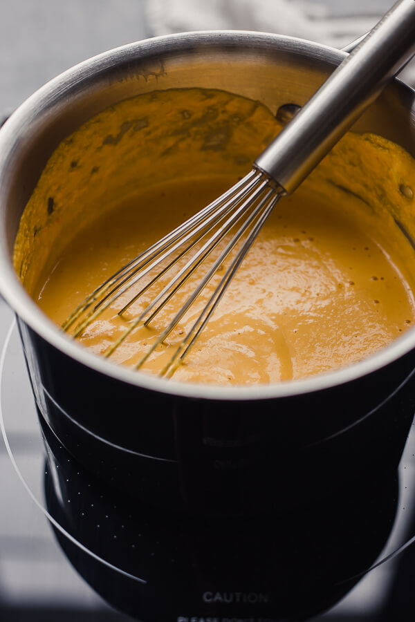 vegan queso in a pot with a whisk