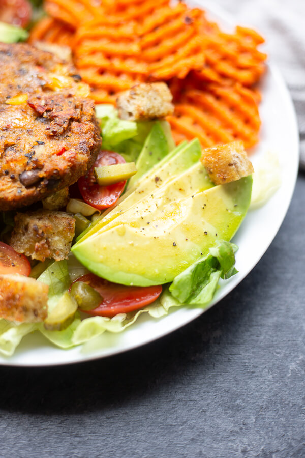 vegan veggie burger salad on a plate with sweet potato fries