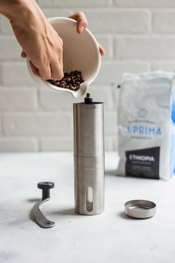 scooping coffee beans into a grinder