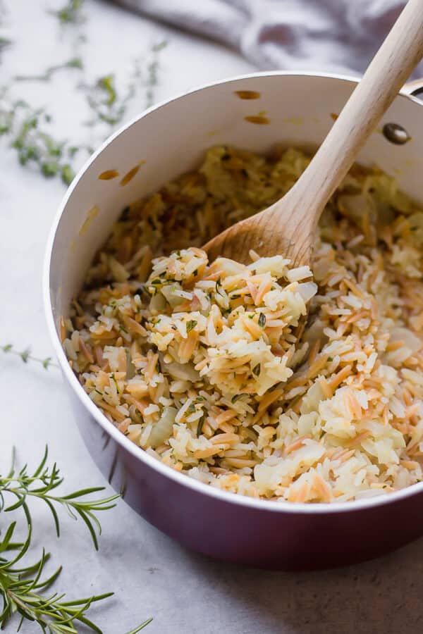 a pot of garlic and herb rice pilaf with a wooden spoon