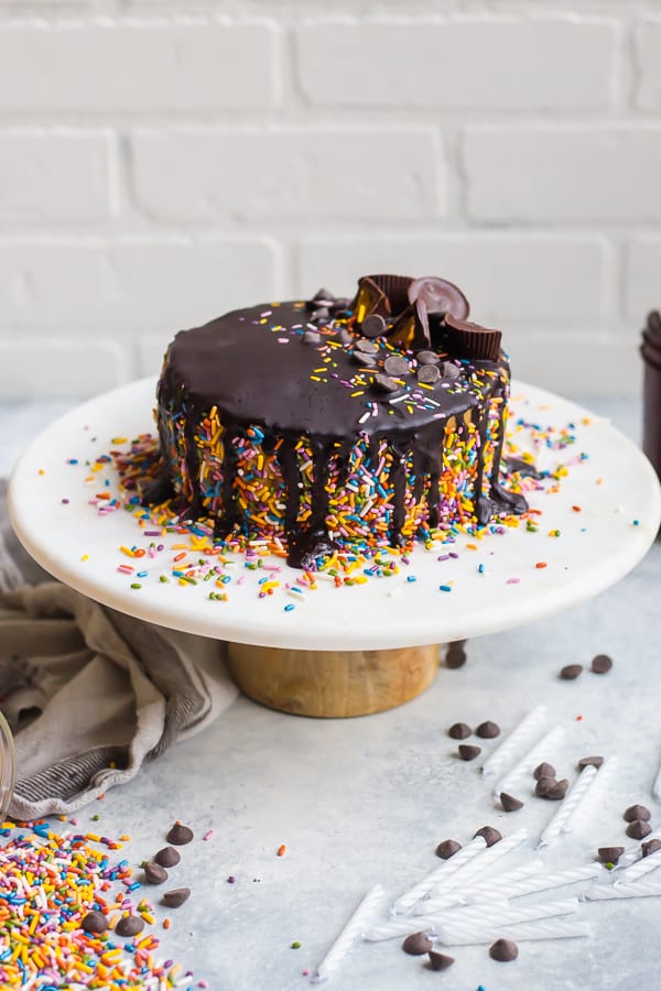 vegan buckeye cake on a cake stand with sprinkles and candles