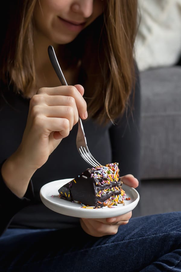 girl eating a piece of cake on a white plate