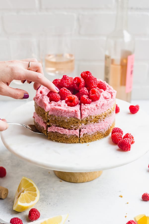 a girl slicing a vegan lemon raspberry cake