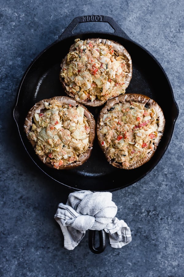 unbaked vegan crab cake-stuffed portobello mushrooms in a cast-iron skillet