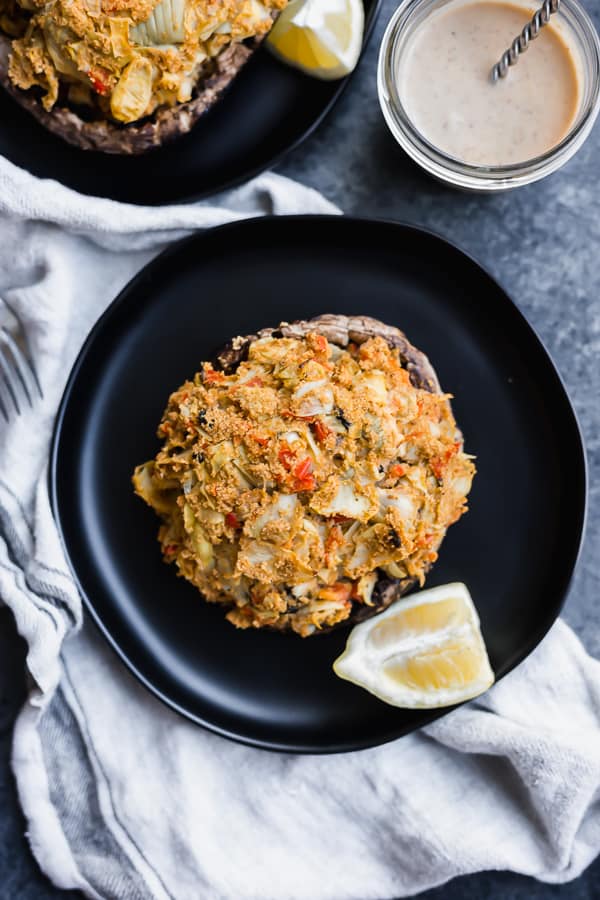 a vegan crab caked-stuffed portobello mushroom on a plate with a lemon slice