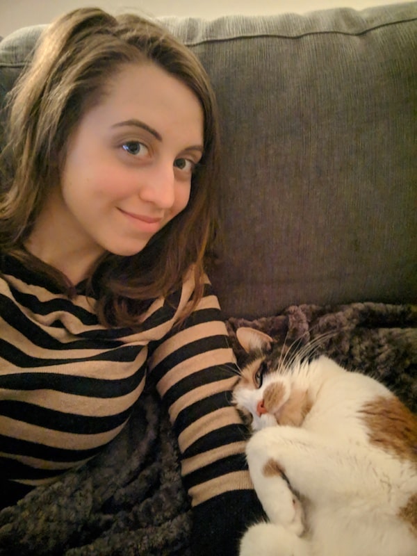 cute calico cuddling up to a girl smiling at the camera