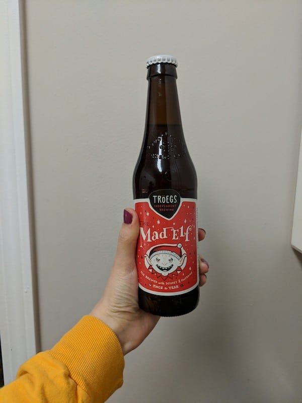 a hand holding a bottle of Tröegs Mad Elf beer