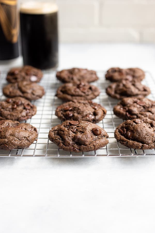 A cooling rack of Chocolate Beer Cookies with a cup of beer in the background
