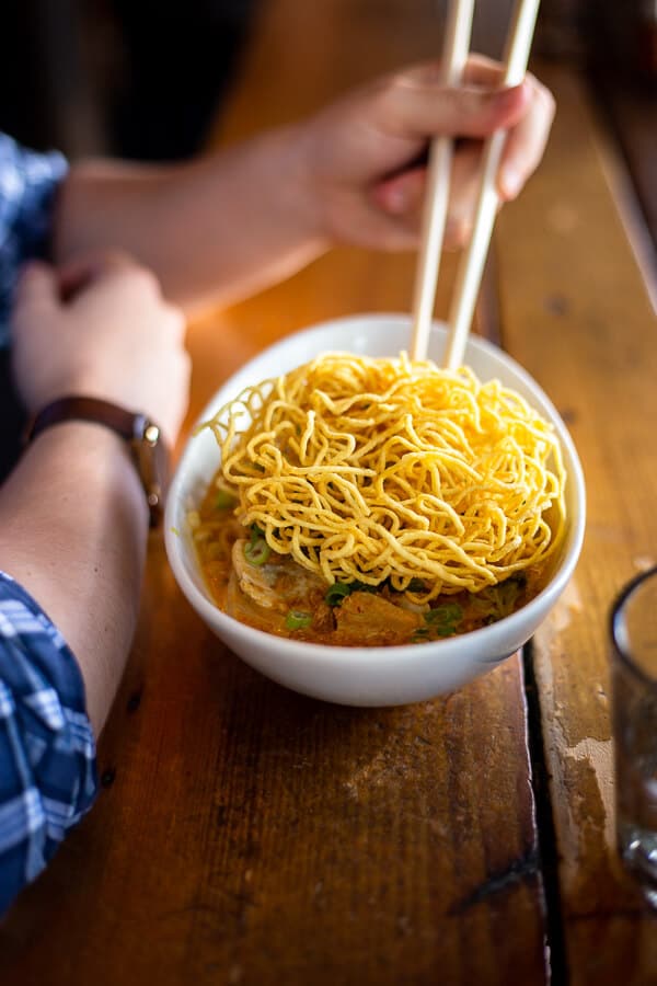 a bowl of curry with chopsticks on a wooden table