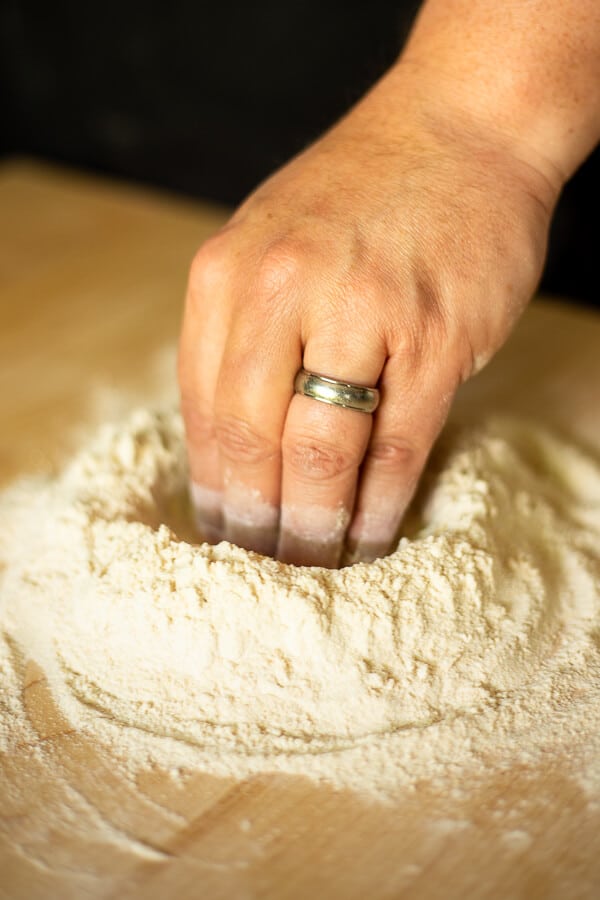 a hand making a well in flour
