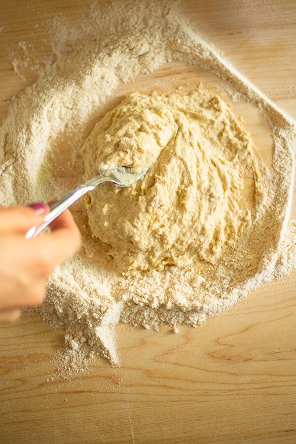a fork mixing homemade pasta dough on a wooden surface