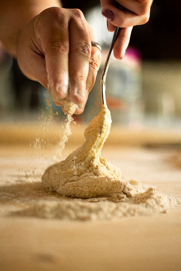 a hand sprinkling flour on pasta dough