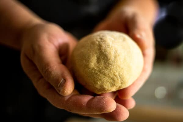 two hands holding a ball of pasta dough