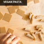 a hand folding squares of homemade pasta dough into garganelli