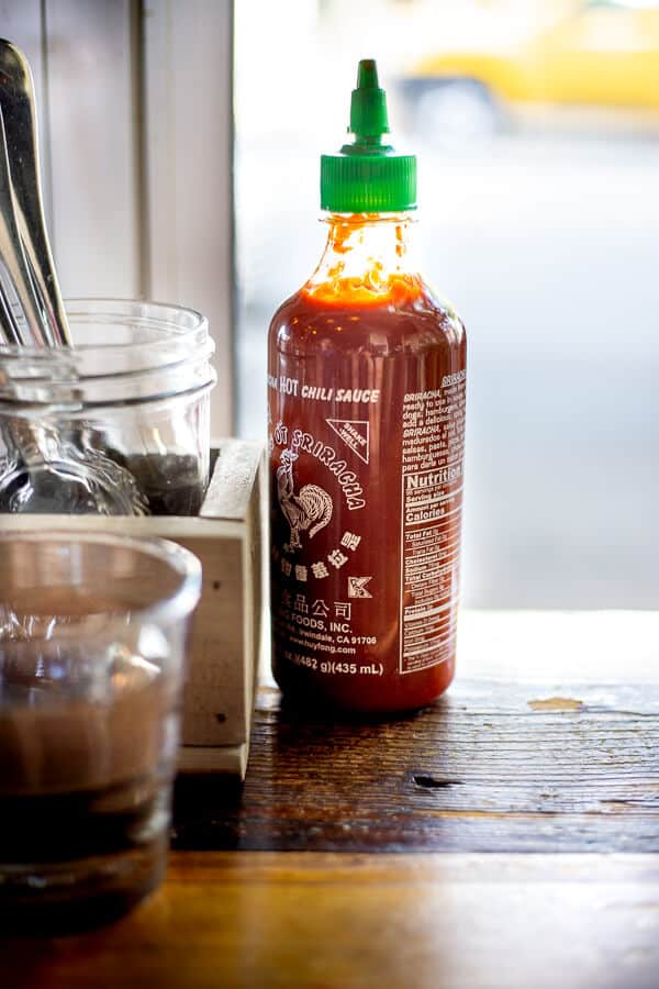 Sriracha on a table in front of a window