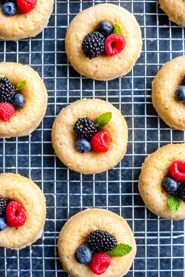 baked vegan lemon donuts with fresh berries on top on a cooling rack