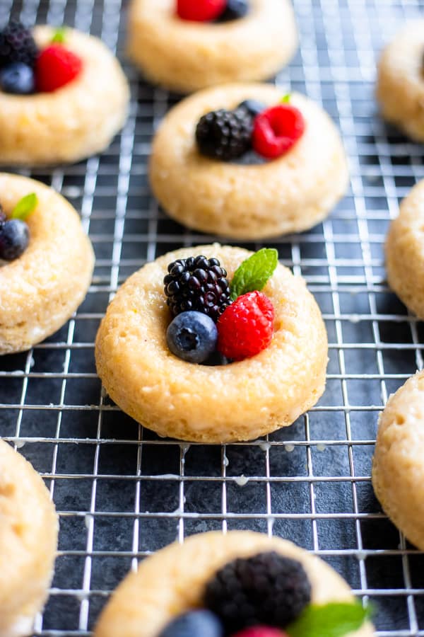 baked vegan lemon donuts with berries and mint on top on a cooling rack