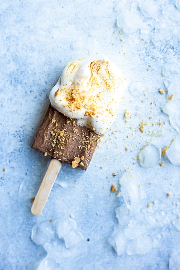 vegan s'mores popsicle on a blue background with ice surrounding it