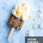 vegan s'mores popsicle on a blue background with ice surrounding it with the name written on it