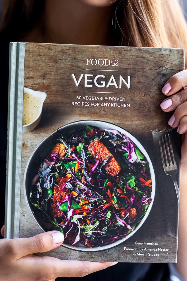 A girl holding the Food52 Vegan cookbook
