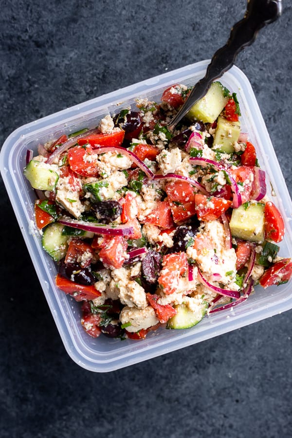 A Vegan Greek Salad with Tofu Feta in a travel container with a fork
