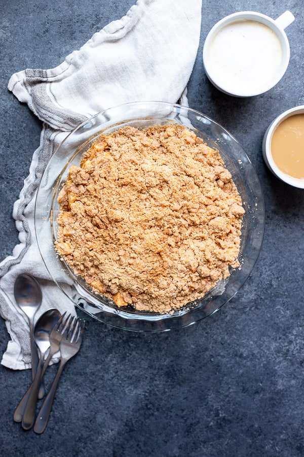Snickerdoodle Apple Crisp in a pie plate with two cups of coffee and silverware