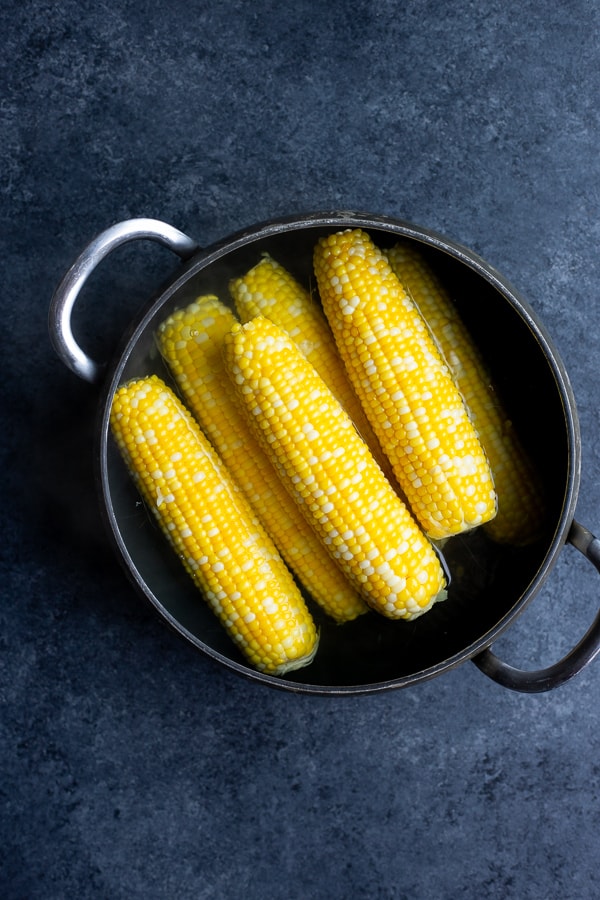 a pot of corn on the cob in water