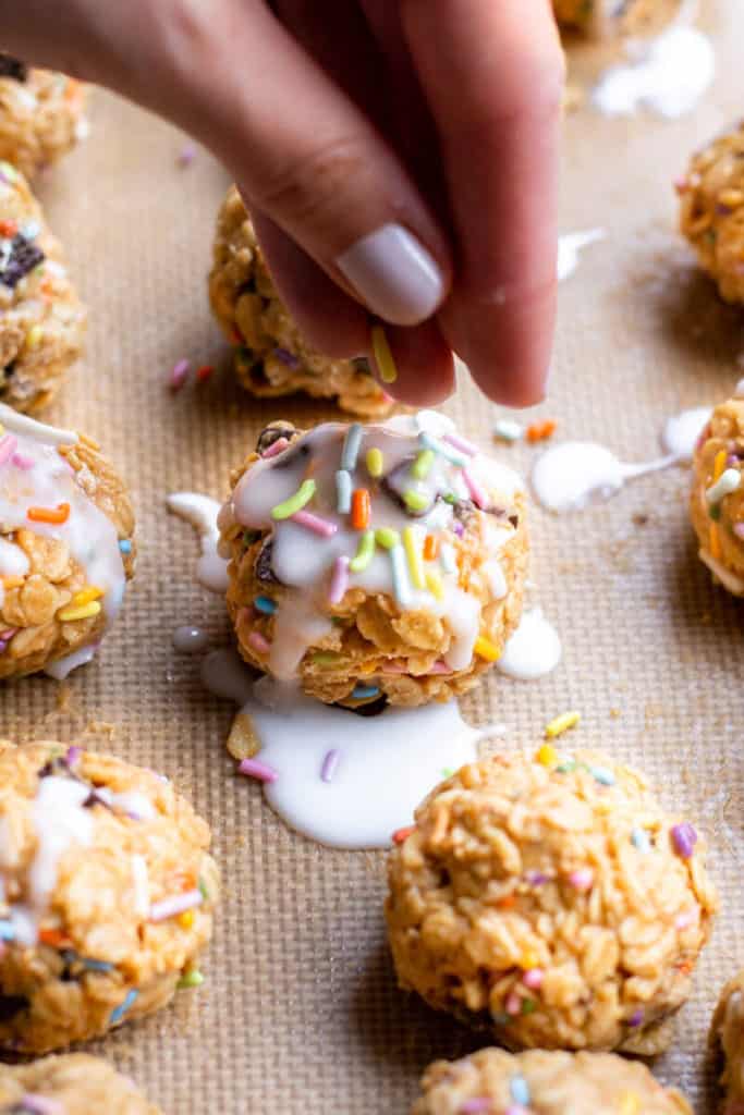 a hand dropping sprinkles on a funfetti no-bake cookie