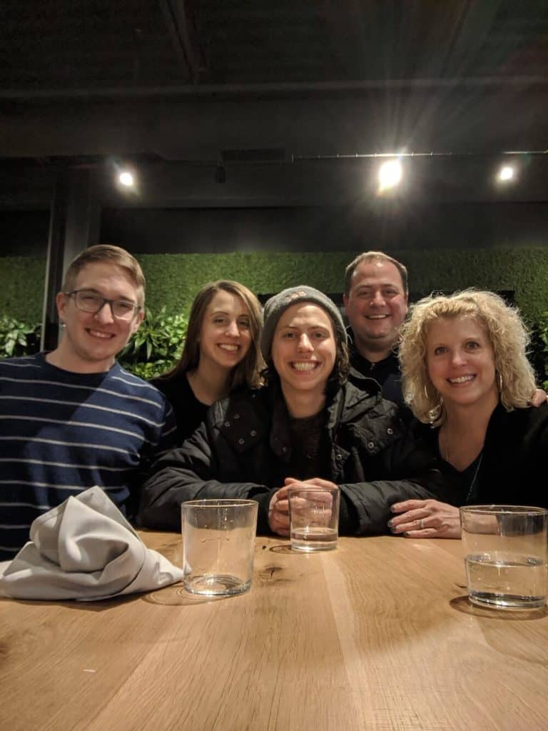 Five people smiling at the camera at the end of a table