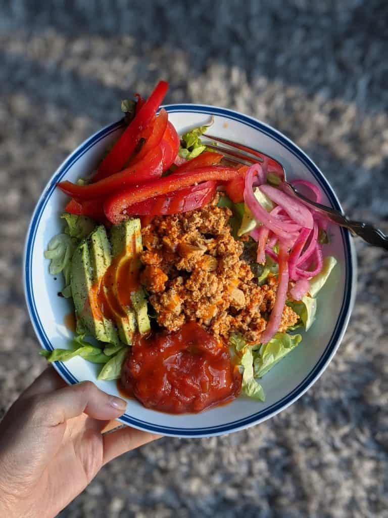 a vegan burrito bowl with peppers, onion, avocado, salsa, and sofritas