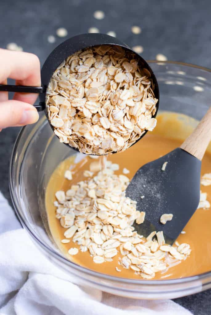a measuring cup full of oats being poured into a large bowl