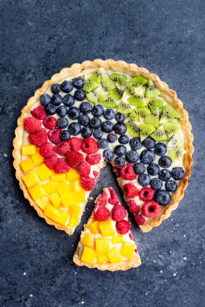 a vegan cream cheese fruit tart with a slice taken out of it
