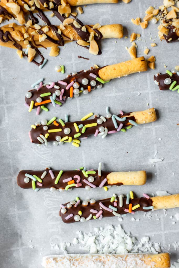 vegan chocolate-covered pretzels with sprinkles on a baking sheet