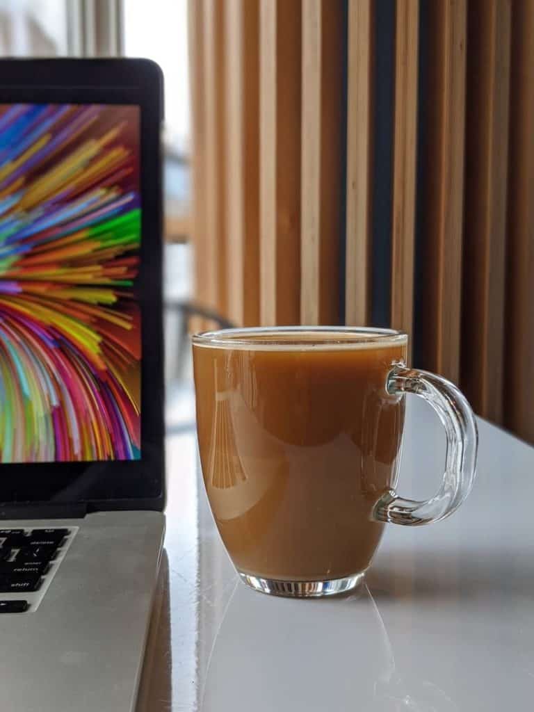 a mug of coffee and a computer on a table at La Prima in Pittsburgh, Pennsylvania