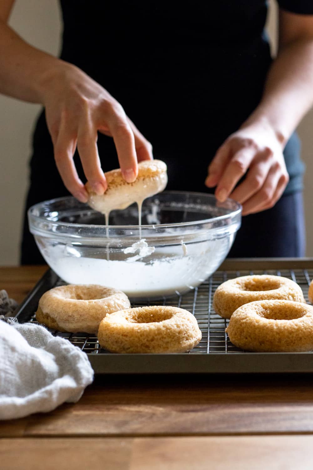 girl dipping baked vanilla bean donuts into glaze