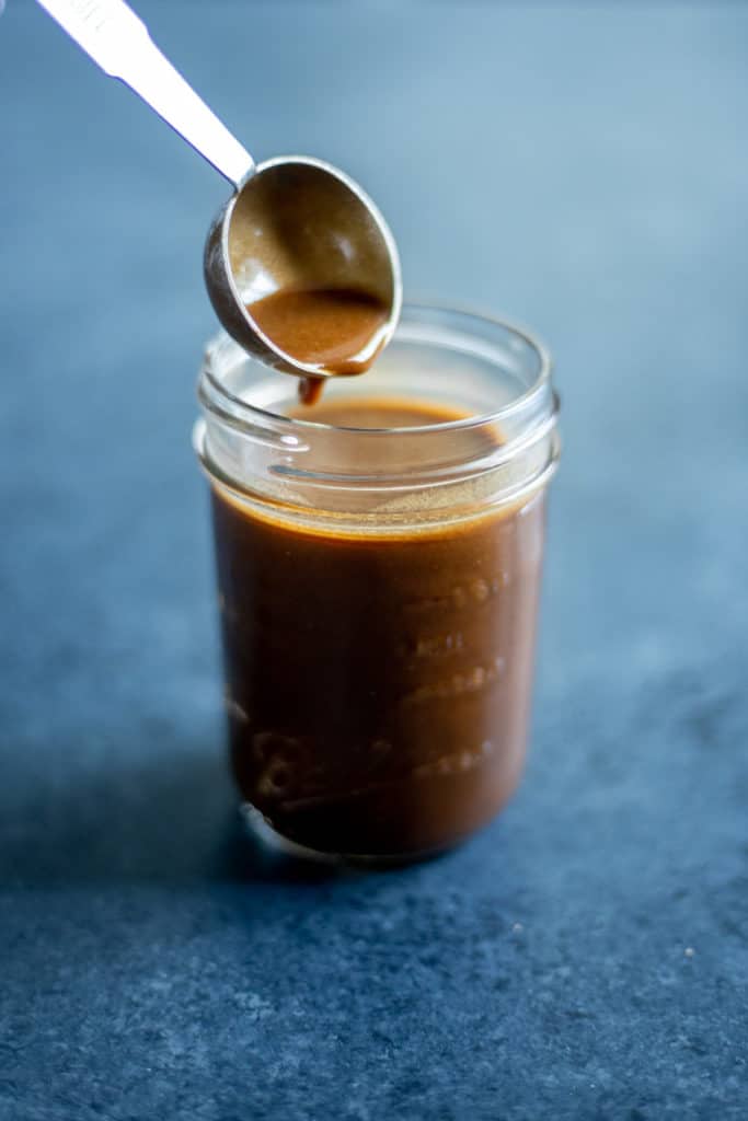 a spoon dipping into a jar of creamy balsamic vinaigrette
