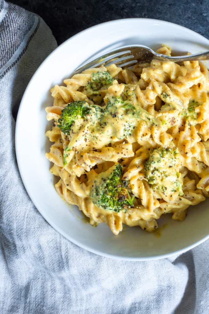 a bowl full of pasta, roasted broccoli, and instant pot vegan cheese sauce