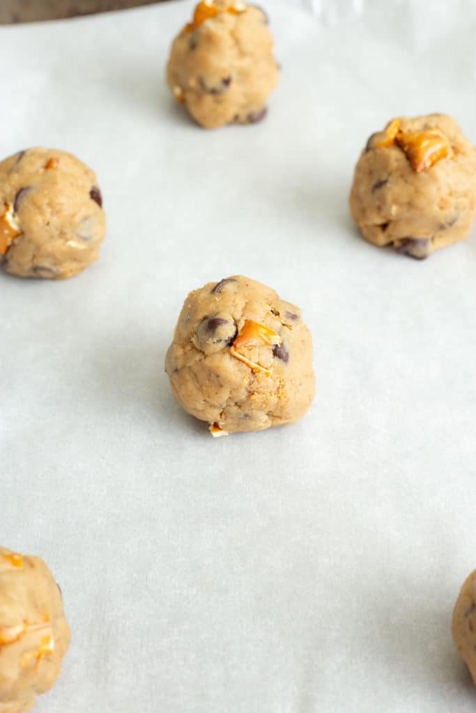 balls of vegan peanut butter pretzel chocolate chip cookie dough on a baking sheet