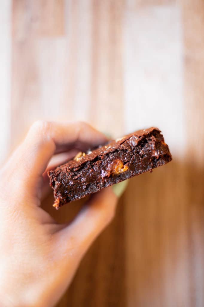 a hand holding a vegan peanut butter cup brownie