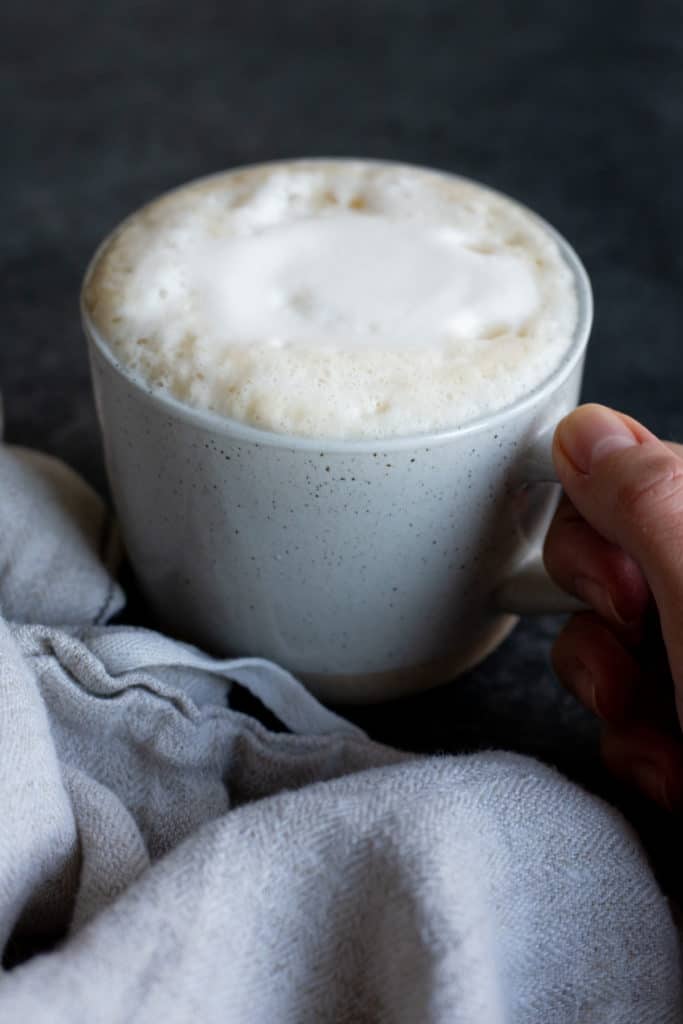 A hand holding a the handle of a mug of a ginger latte